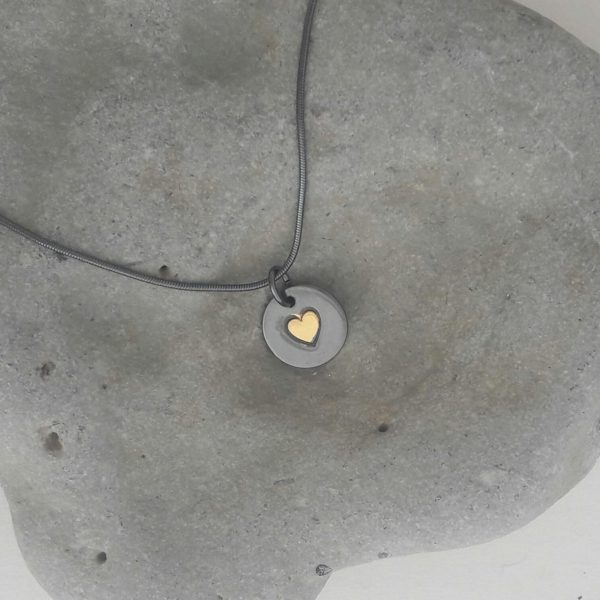 Rund handgjord silverberlock med guldhjärta, mörkt oxiderad variant,14 x 14 mm., mot ljust grå bakgrund.