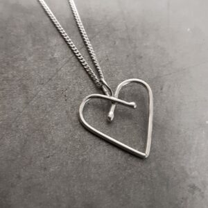 Unikt hjärta gjort för hand av silvertråd mot grå bakgrund.